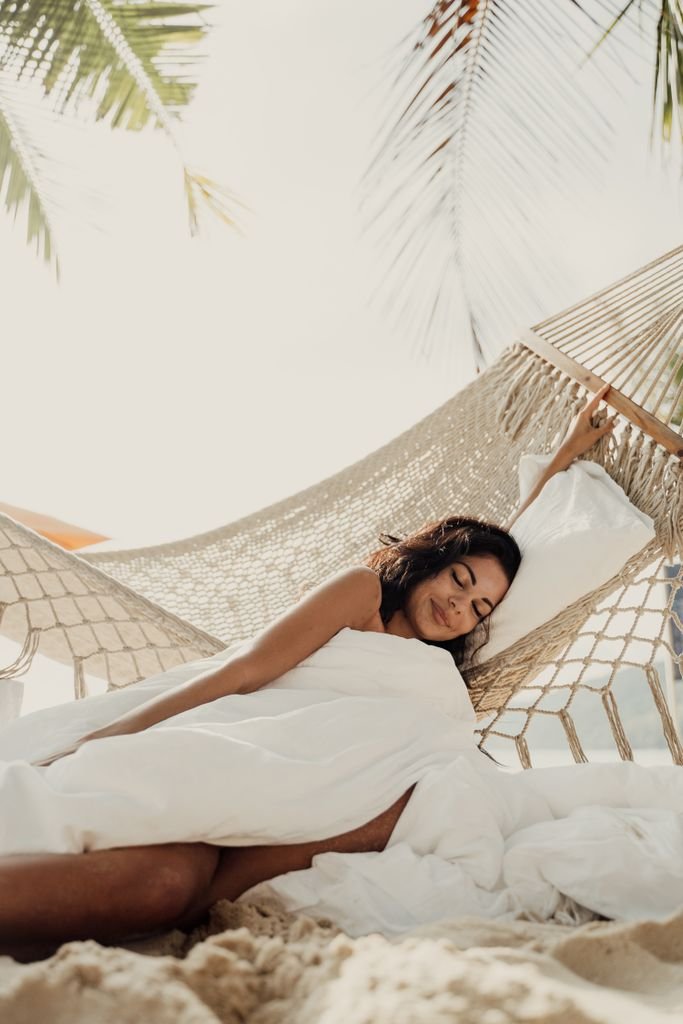 Serene image of a woman relaxing in a hammock by the beach, capturing a peaceful vacation vibe.