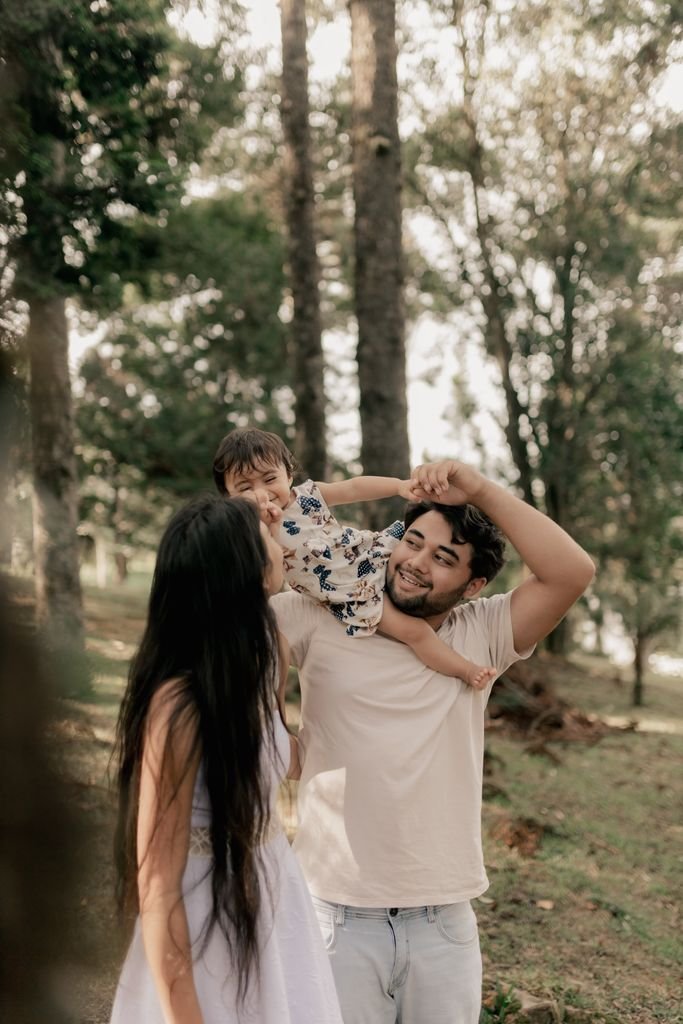 Young family spending quality time playing in a lush green forest, enjoying nature together.