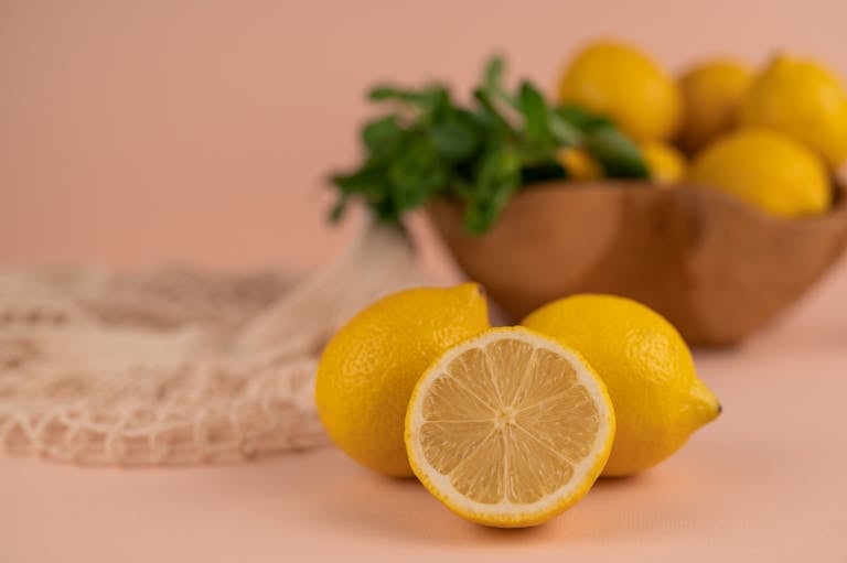 Vibrant lemons on a soft pink backdrop, perfect for culinary themes.