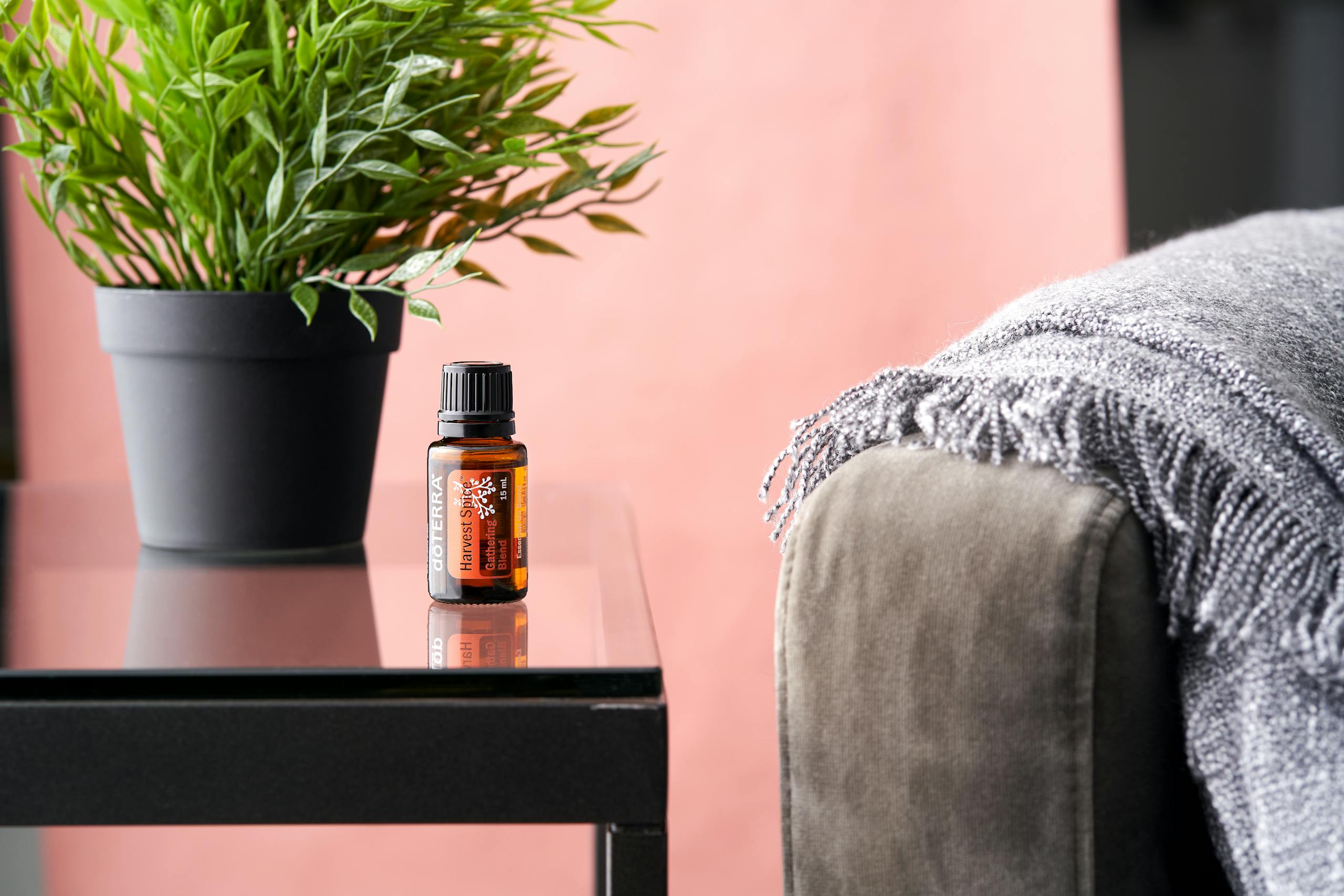 A glass bottle of essential oil next to a lush plant on a sleek table, embodying serenity.