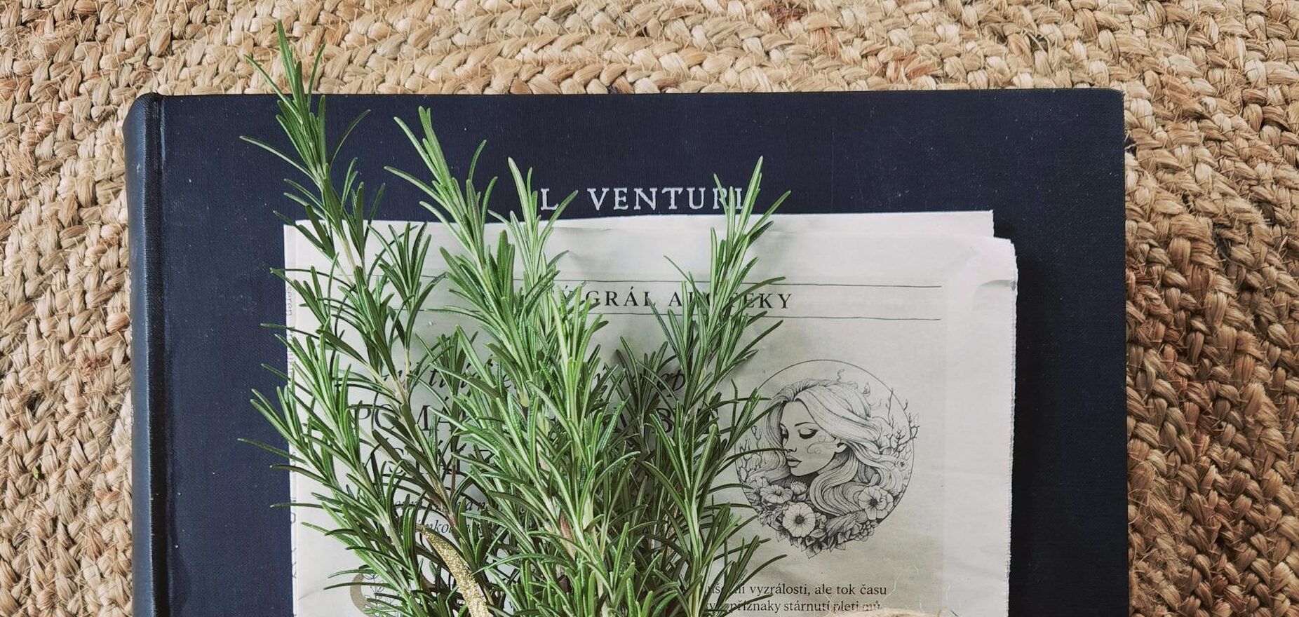A bundle of fresh rosemary, scissors, and twine on a rustic mat, evoking a cozy artisanal feel.